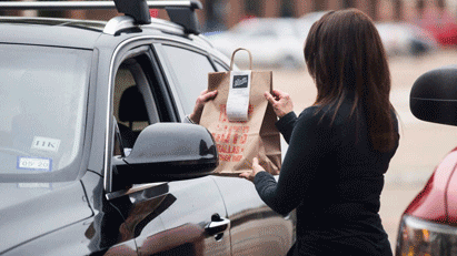 woman handing to go food through car window