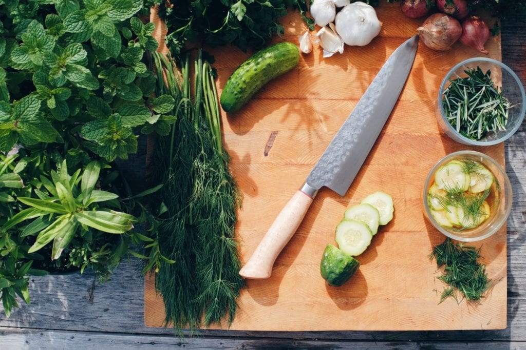 chef knife on cutting board with fresh herbs